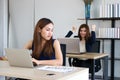 Young angry envious Asian business woman looking successful competitor colleague in office Royalty Free Stock Photo