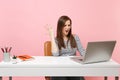 Young angry irritated woman spreading hand working on project while sitting at office with laptop isolated on pastel Royalty Free Stock Photo