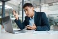 Young angry mixed race businessman working on a laptop at work. One hispanic businessperson looking stressed and upset