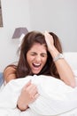 Young angry woman on the bed pulling her hair and screaming Royalty Free Stock Photo