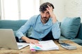 Angry man paying bills as home with laptop and calculator