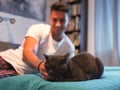 Young Animal-Lover Man on a Bed, Petting his Cat Pet.