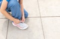 Young anonymous girl, elementary school age child tying her shoe, shoelaces. Child tying shoes outdoors hands closeup, detail