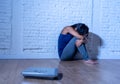 Young anorexic teenager woman sitting alone on ground looking at the scale worried and depressed in dieting and eating disorder