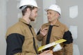 Young apprentice with professional plasterer