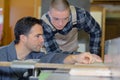 Young apprentice with teacher working on piece wood