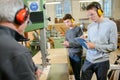 Young apprentices protecting ears from noisy machinery