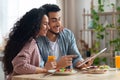 Young Arab Couple Using Digital Tablet In Kitchen While Having Breakfast Royalty Free Stock Photo