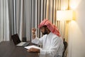 a young Arab entrepreneur who is working writing books with a pen and using a laptop