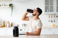 Young Arab guy drinking protein shake from bottle at kitchen, copy space. Body care concept Royalty Free Stock Photo