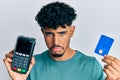 Young arab handsome man holding dataphone and credit card depressed and worry for distress, crying angry and afraid Royalty Free Stock Photo