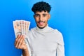 Young arab handsome man holding 10 united kingdom pounds banknotes looking positive and happy standing and smiling with a