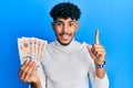 Young arab handsome man holding 10 united kingdom pounds banknotes smiling with an idea or question pointing finger with happy