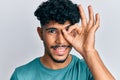 Young arab handsome man wearing casual clothes smiling happy doing ok sign with hand on eye looking through fingers Royalty Free Stock Photo