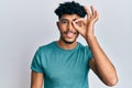 Young arab handsome man wearing casual clothes smiling happy doing ok sign with hand on eye looking through fingers Royalty Free Stock Photo