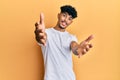 Young arab handsome man wearing casual white tshirt looking at the camera smiling with open arms for hug Royalty Free Stock Photo