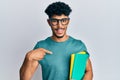 Young arab handsome man wearing glasses and holding books pointing finger to one self smiling happy and proud Royalty Free Stock Photo