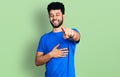 Young arab man with beard wearing casual blue t shirt laughing at you, pointing finger to the camera with hand over body, shame Royalty Free Stock Photo