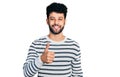 Young arab man with beard wearing casual striped sweater doing happy thumbs up gesture with hand