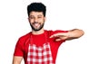 Young arab man with beard wearing cook apron gesturing with hands showing big and large size sign, measure symbol Royalty Free Stock Photo