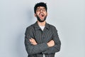 Young arab man with beard wearing glasses with arms crossed gesture angry and mad screaming frustrated and furious, shouting with Royalty Free Stock Photo