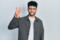 Young arab man with beard wearing glasses showing and pointing up with fingers number three while smiling confident and happy Royalty Free Stock Photo