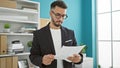 Young arab man business worker reading document with serious face at the office Royalty Free Stock Photo