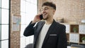 Young arab man business worker smiling confident talking on smartphone at office Royalty Free Stock Photo