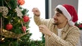 Young arab man decorating christmas tree at home Royalty Free Stock Photo