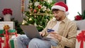 Young arab man decorating christmas tree at home Royalty Free Stock Photo