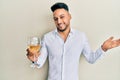 Young arab man drinking a glass of white wine celebrating achievement with happy smile and winner expression with raised hand Royalty Free Stock Photo