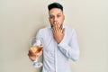 Young arab man drinking a glass of white wine covering mouth with hand, shocked and afraid for mistake Royalty Free Stock Photo