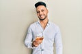 Young arab man drinking a glass of white wine looking positive and happy standing and smiling with a confident smile showing teeth Royalty Free Stock Photo