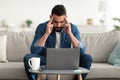 Young Arab man having headache, tired of working on laptop at home office Royalty Free Stock Photo