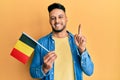 Young arab man holding belgium flag smiling with an idea or question pointing finger with happy face, number one Royalty Free Stock Photo