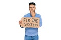 Young arab man holding fix the system banner cardboard covering mouth with hand, shocked and afraid for mistake Royalty Free Stock Photo