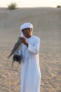 Young arab man holding a hawk in the desert near Dubai, UAE