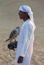 Young arab man holding a hawk in the desert near Dubai, UAE