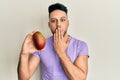Young arab man holding mango covering mouth with hand, shocked and afraid for mistake Royalty Free Stock Photo