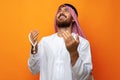 Young Arab man holding traditional beads against orange background