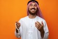 Young Arab man holding traditional beads against orange background