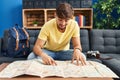 Young arab man looking city map sitting on sofa at home Royalty Free Stock Photo
