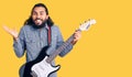 Young arab man playing electric guitar celebrating victory with happy smile and winner expression with raised hands Royalty Free Stock Photo