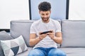 Young arab man playing video game sitting on sofa at home Royalty Free Stock Photo