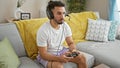 Young arab man playing video game sitting on sofa at home Royalty Free Stock Photo