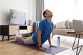Young arab man practicing pilates with pc, watching online tutorials and standing in cobra pose Royalty Free Stock Photo