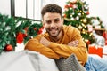 Young arab man smiling happy sitting on the sofa by christmas tree at home Royalty Free Stock Photo