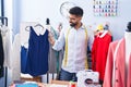 Young arab man tailor smiling confident holding t shirts at tailor shop Royalty Free Stock Photo