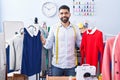 Young arab man tailor smiling confident holding t shirts at tailor shop Royalty Free Stock Photo