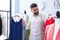 Young arab man tailor smiling confident holding t shirts at tailor shop Royalty Free Stock Photo